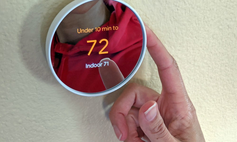 A person operating the Google Nest thermostat.