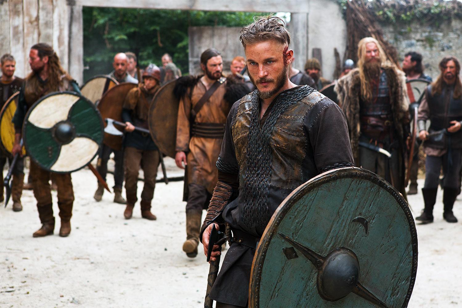 A viking holds a shield in front of an army.