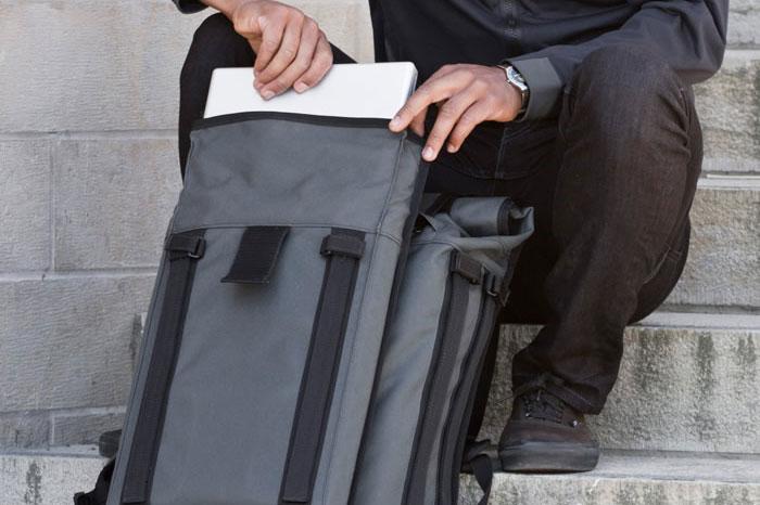 Close up of a person's hands pulling a white item out of a Mission Workshop R6 Arkiv Field Pack.