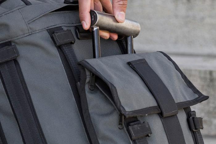 Profile view of a person's hand holding a handle from a Mission Workshop R6 Arkiv Field Pack.