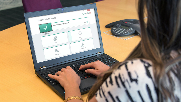 A close up of a woman using a laptop that is displaying Kaspersky software on its screen.