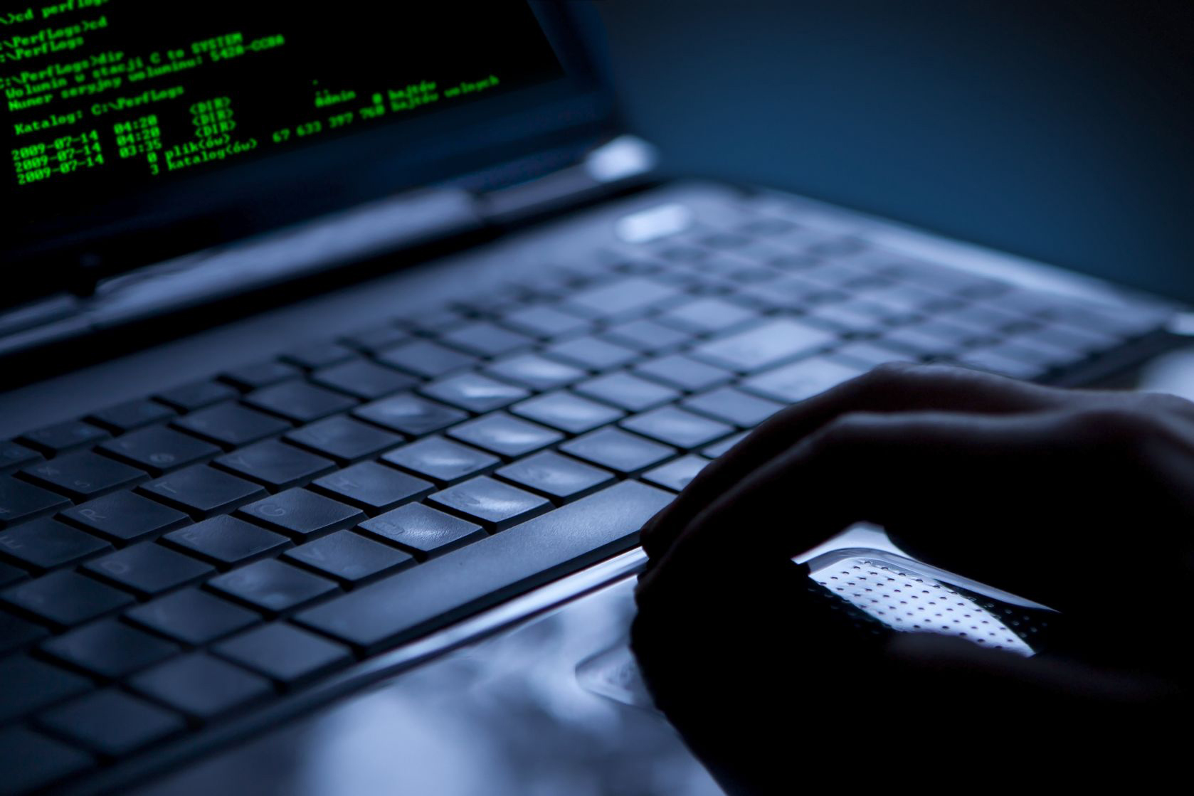 A hand on a laptop in a dark surrounding.