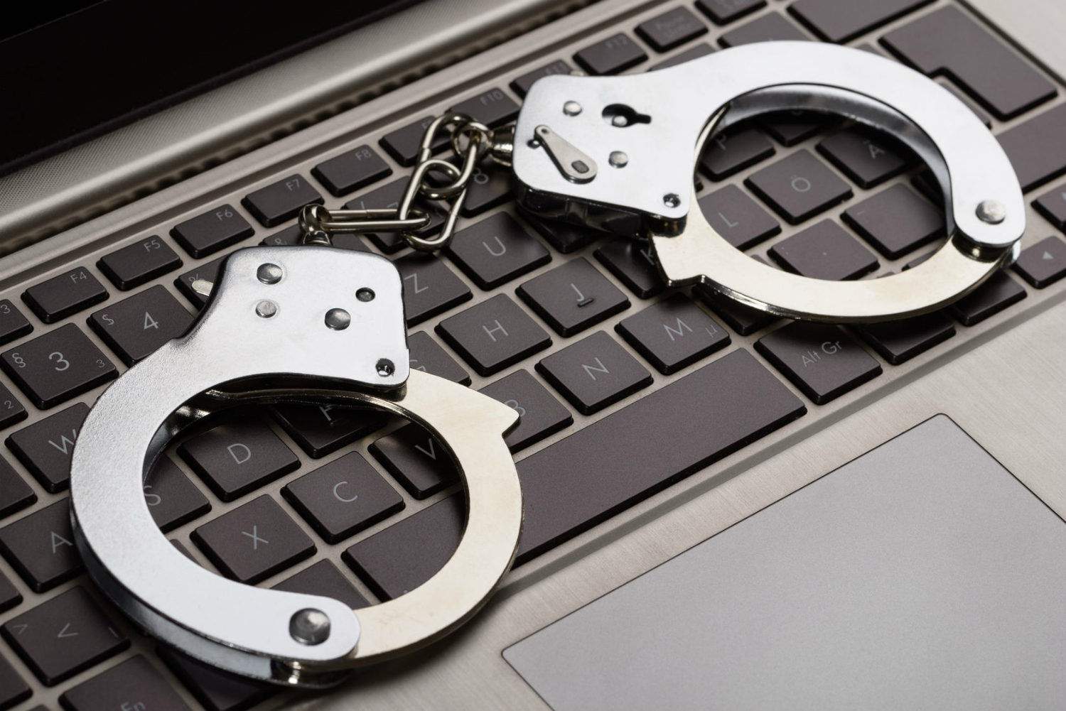 backpage ceo carl ferrer arrested handcuffs lying on laptop keypad