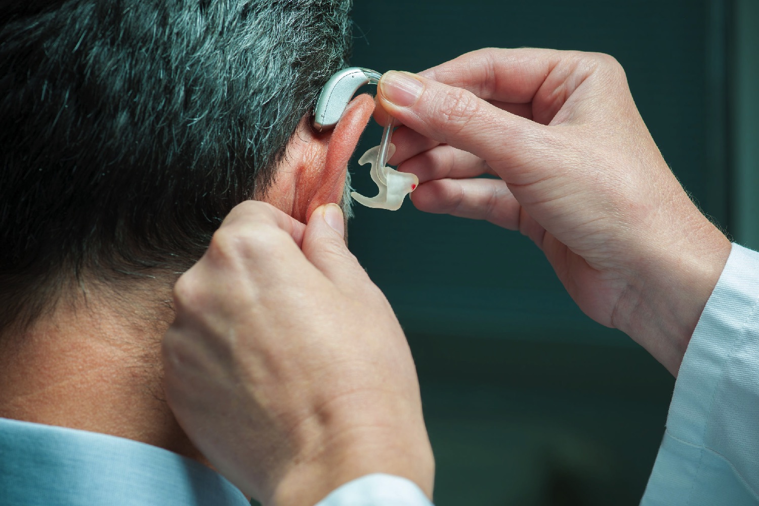 Audiologist fitting a patient's hearing aid.