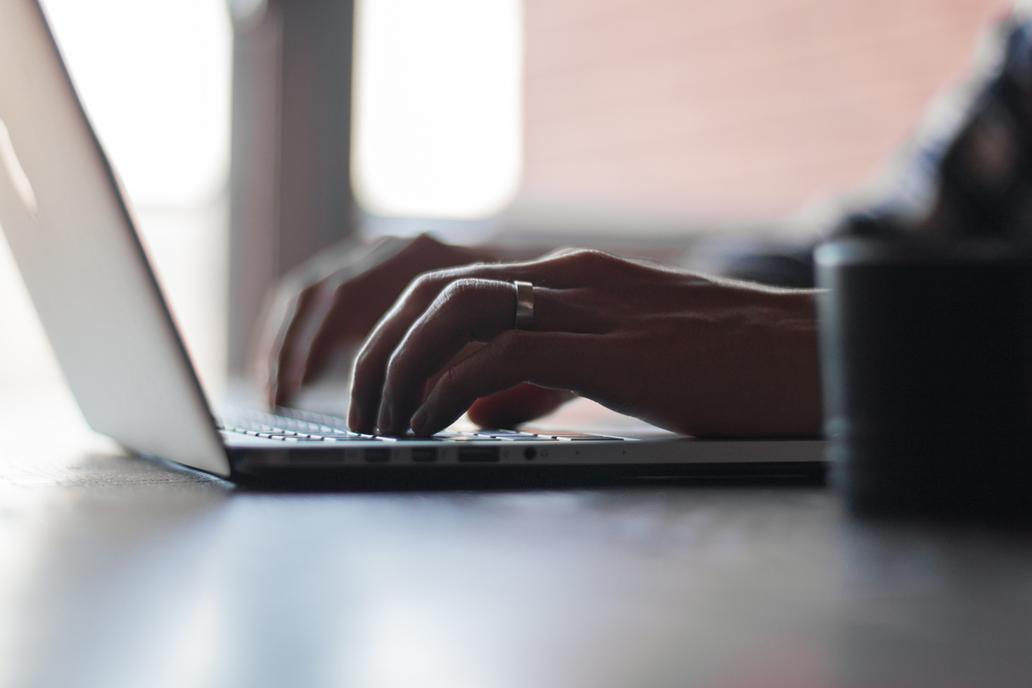 A close up of a person's hands typing on a laptop.