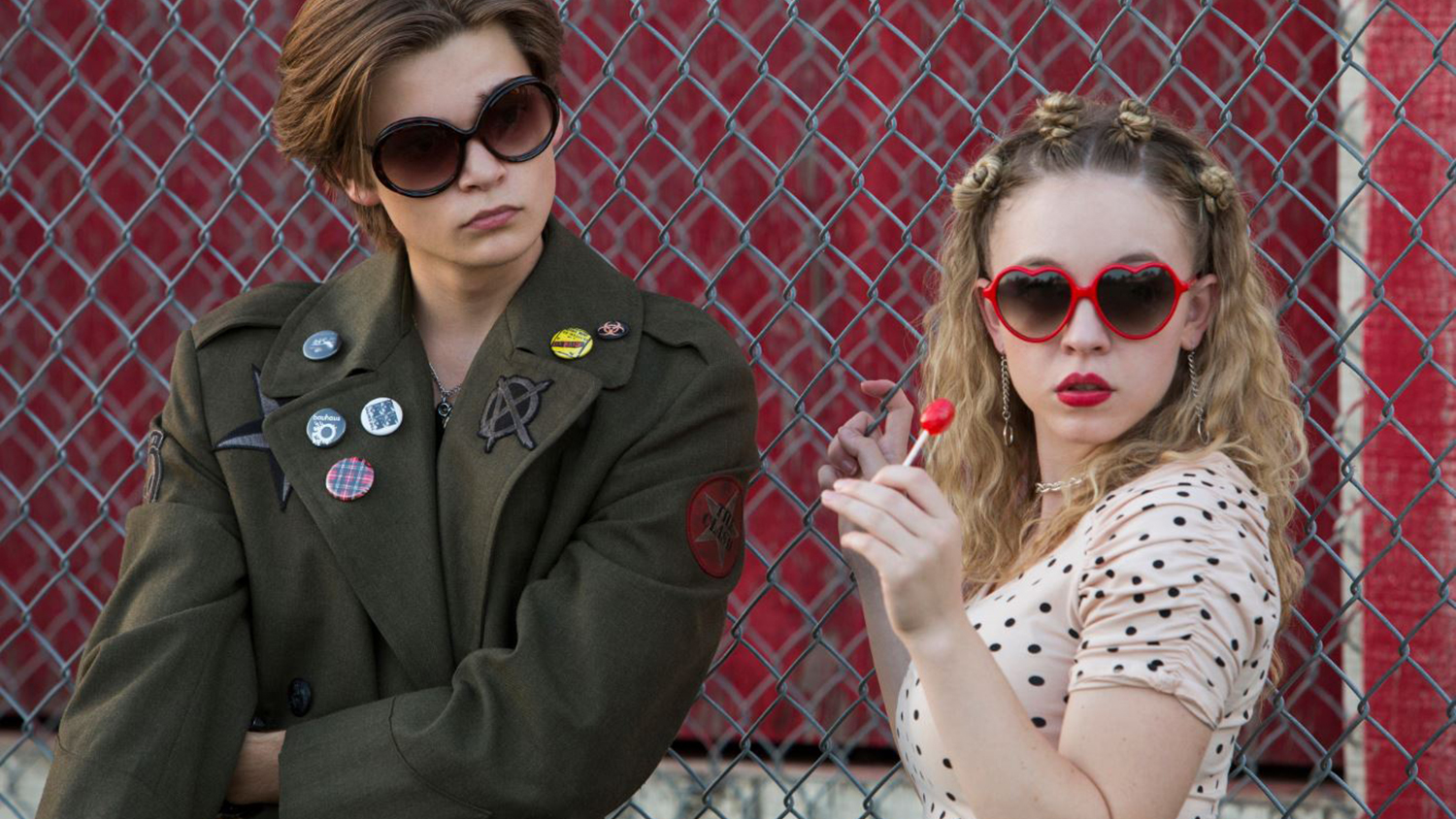 Two girls stand next to each other outside a fence in Everything Sucks!