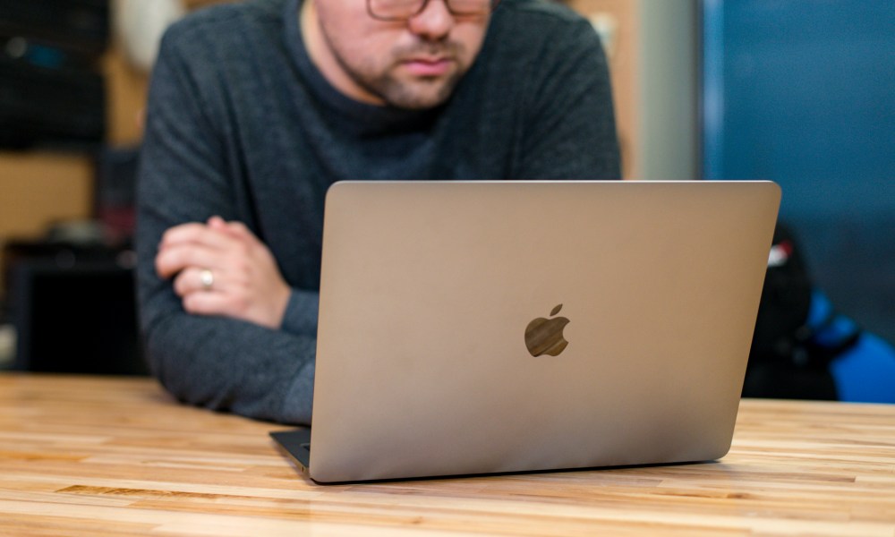 A person working at a 2018 Macbook Air at a wooden table.