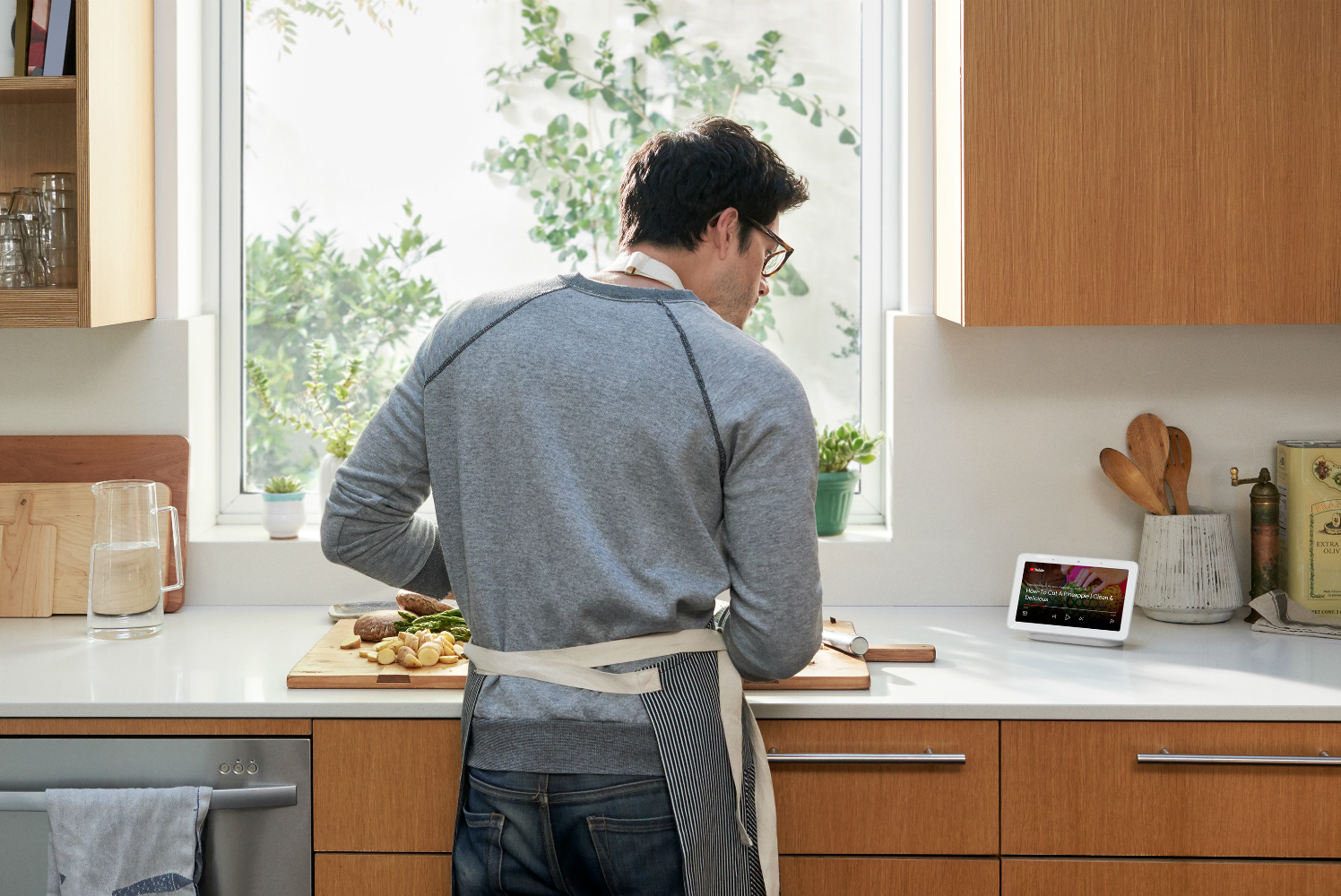 Man in kitchen talking to Google Home.