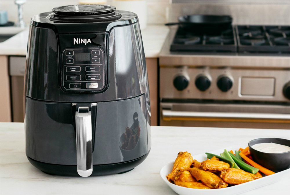 The Ninja 4QT air fryer next to food.