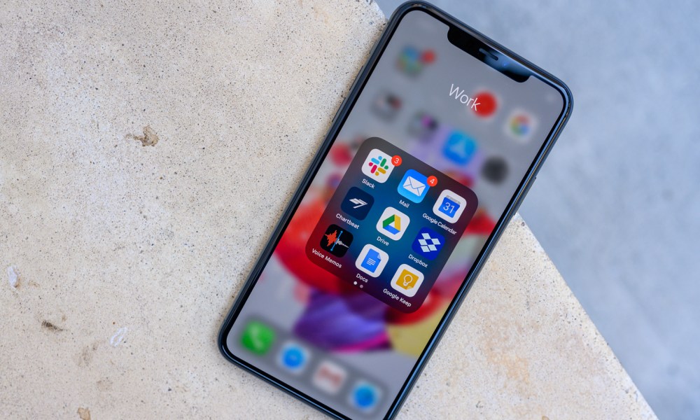 The iPhone 11 Pro Max on concrete with the home screen open and on display.