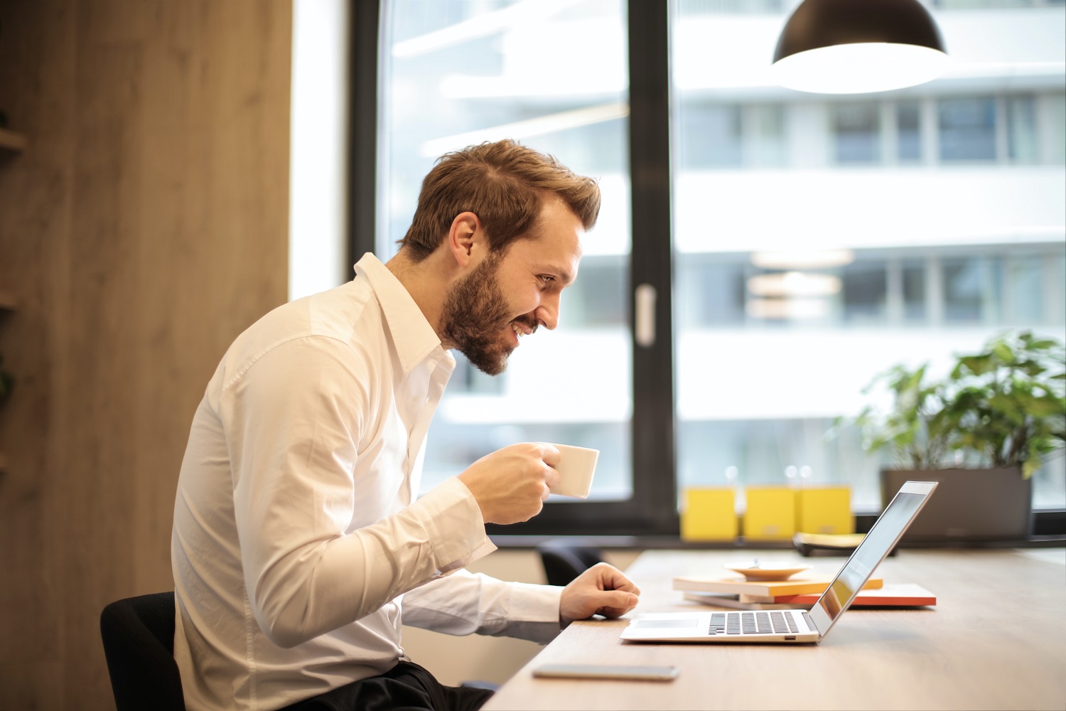 how to use gotomeeting man holding teacup infront of laptop on top table inside 925786