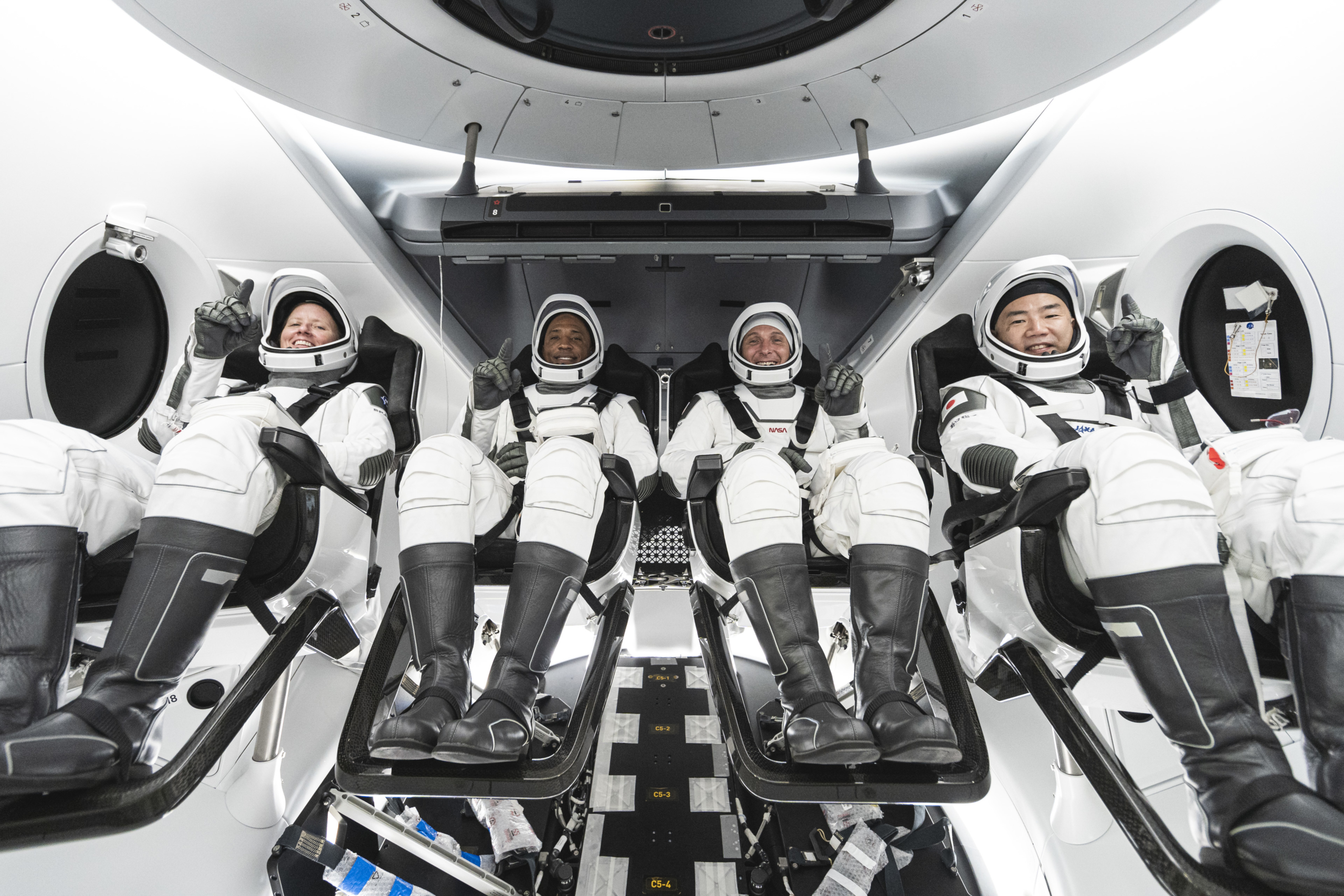 NASA’s SpaceX Crew-1 crew members are seen seated in the company’s Crew Dragon spacecraft during crew equipment interface training.