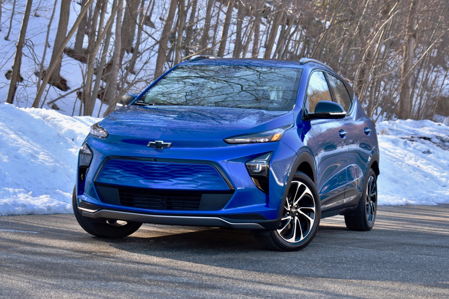 A blue Chevy Bolt against a snowy backdrop.