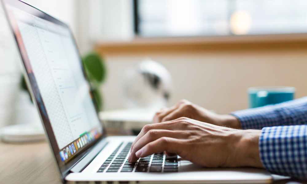 A man's hands typing on a laptop.