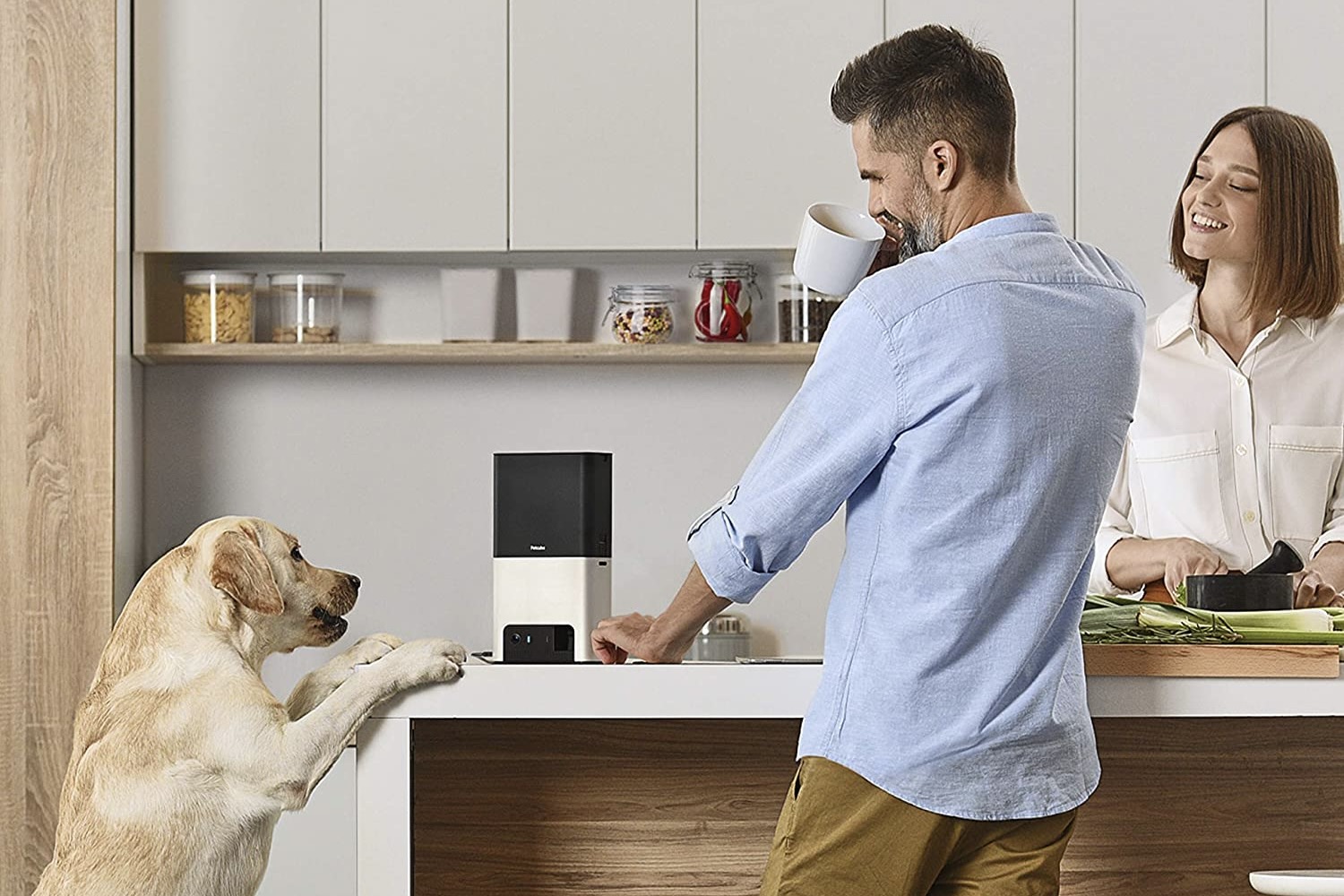 A dog and his human companions surrounding the Petcube Bites 2.