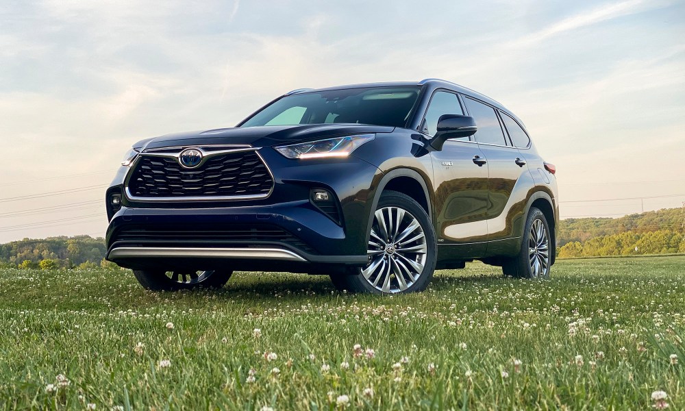 Angled front view of the 2021 Toyota Highlander Hybrid Platinum in a field (driver's side).