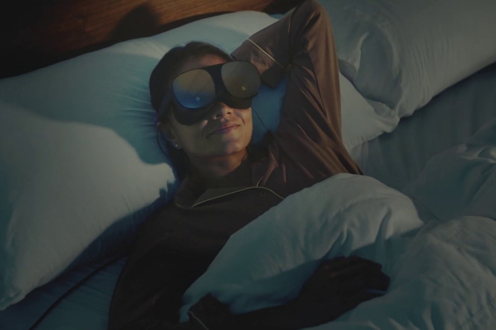 Person lying in bed ready to sleep while wearing HTC Vive Flow standalone VR headset.