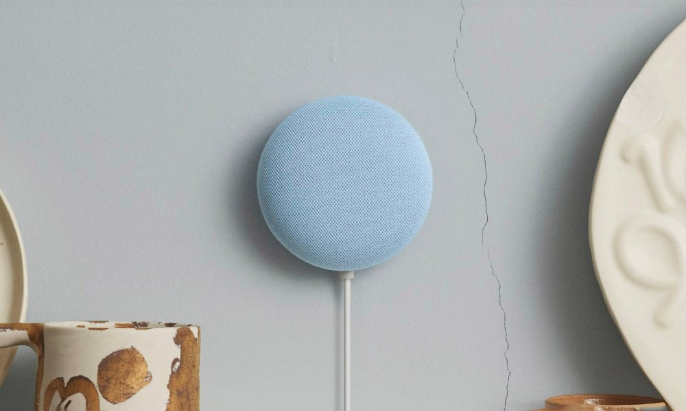 A blue Google Nest Mini mounted on blue/gray wall.