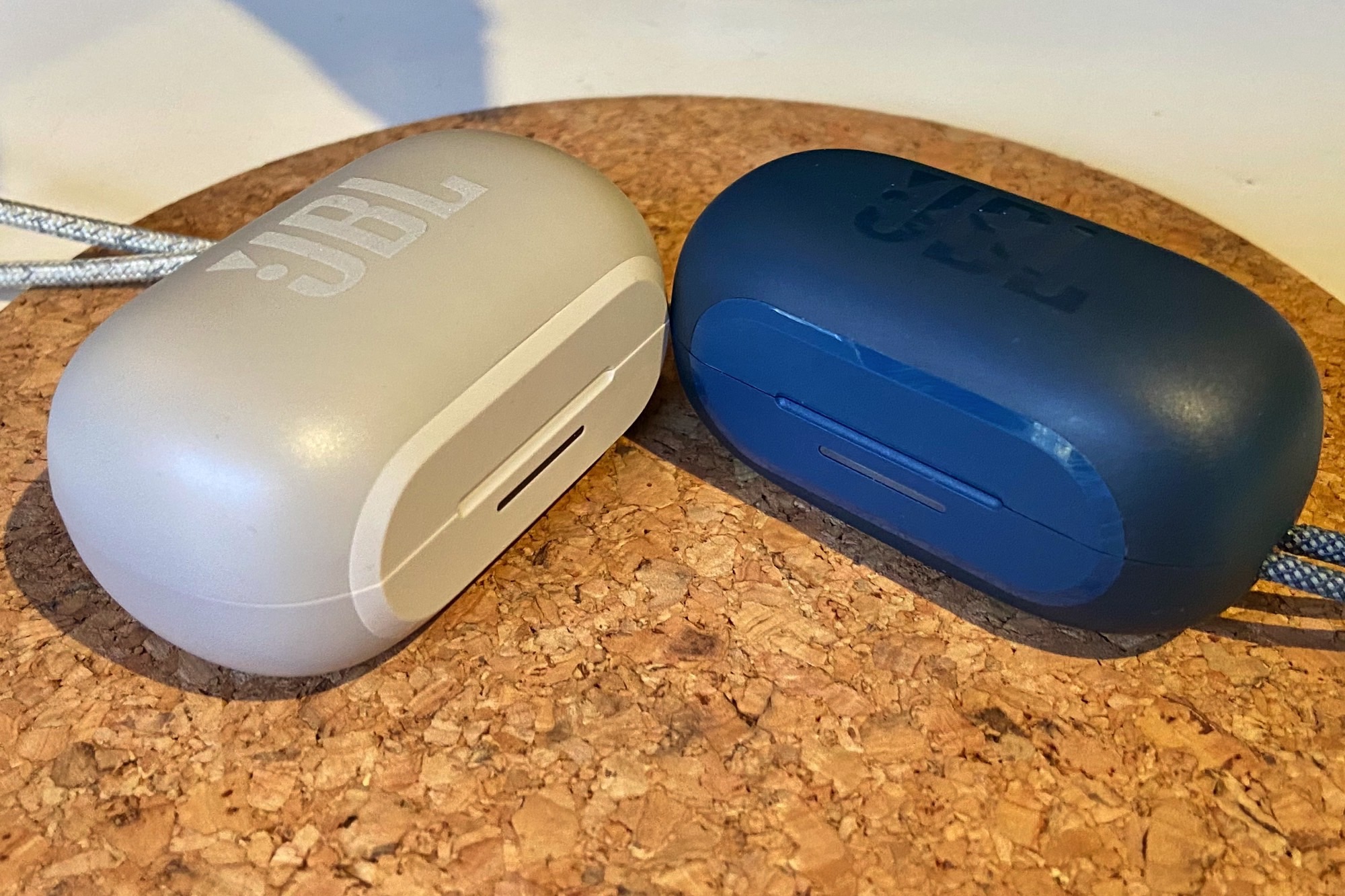 JBL Reflect Flow Pro charging case seen next to JBL Reflect Mini NC charging case.