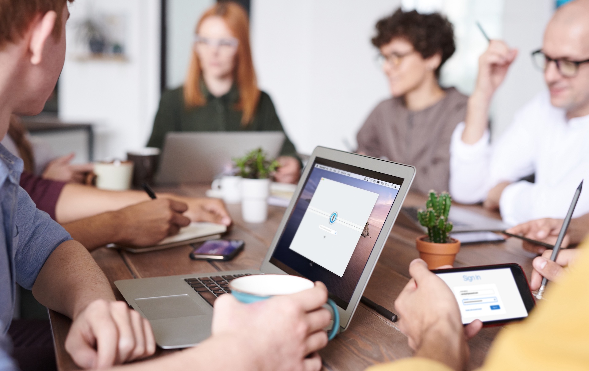 A group of people sitting at a desk looking at 1Password displayed on a screen.