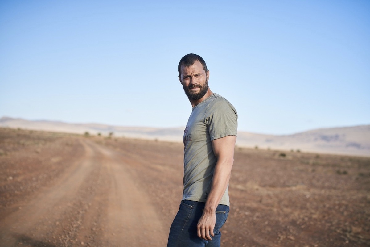 Jamie Dornan driving a car, looking in the rearview mirror at a truck approaching him in a scene from The Tourist.