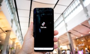 A person's hand holding a phone with the TikTok app on it.