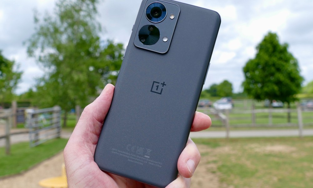 The OnePlus Nord 2T held in a man's hand seen from the back.