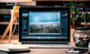 A Macbook sits on a desk with Adobe Lightroom opened on screen.