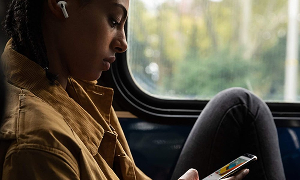 Woman wearing AirPods Pro wireless earbuds on a train.