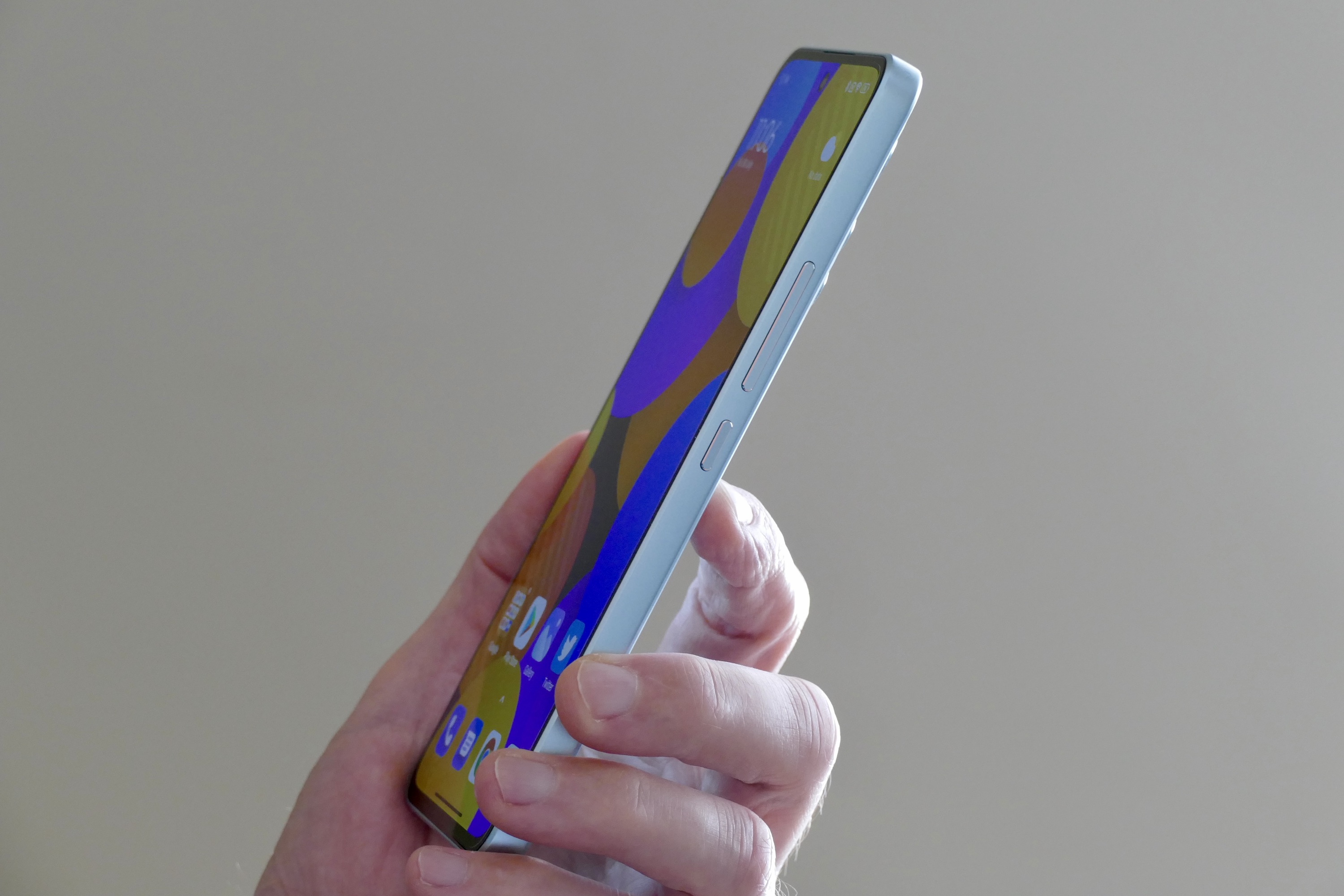 The side of the Xiaomi 12 Lite, held in a mans hand.