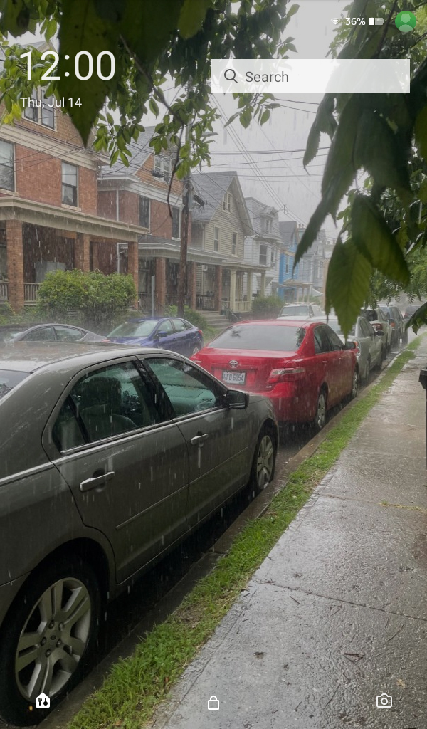 Screenshot of the 2022 Amazon Fire 7's lockscreen which displays the time and a search bar. The background is of a rainy day.