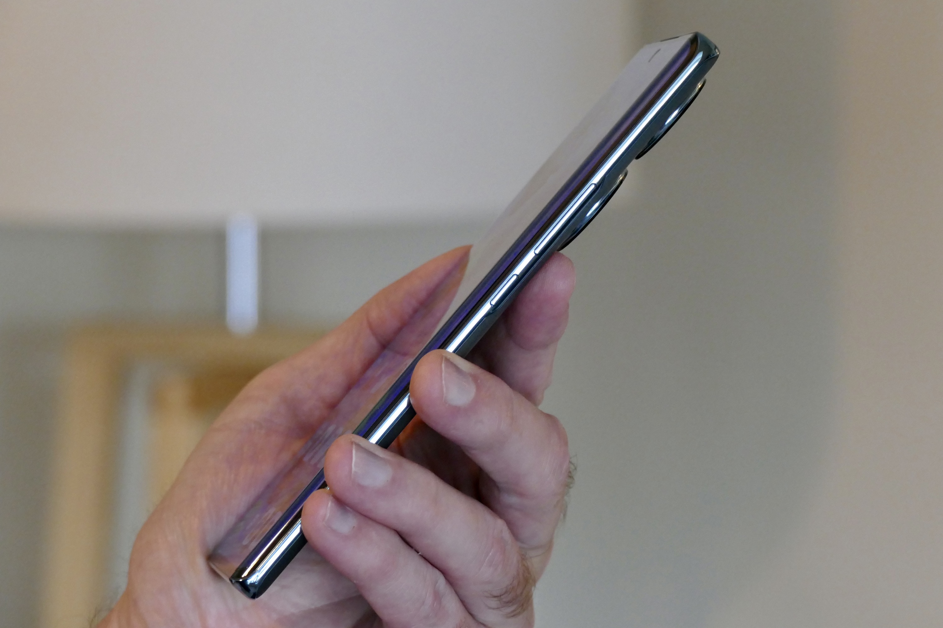 The Honor 70 held in a mans hand and seen from the side.