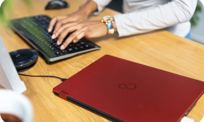 A red Fujitsu laptop on a desk.