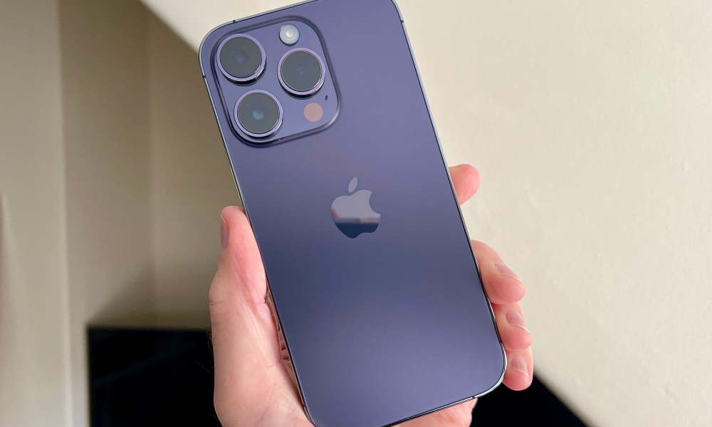 iPhone 14 Pro in Deep Purple, held in a mans hand.