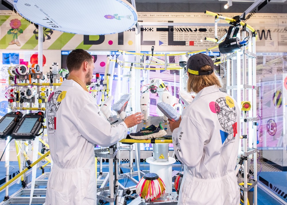 Two Nike staff monitoring BILL, the company's sneaker-cleaning robot.