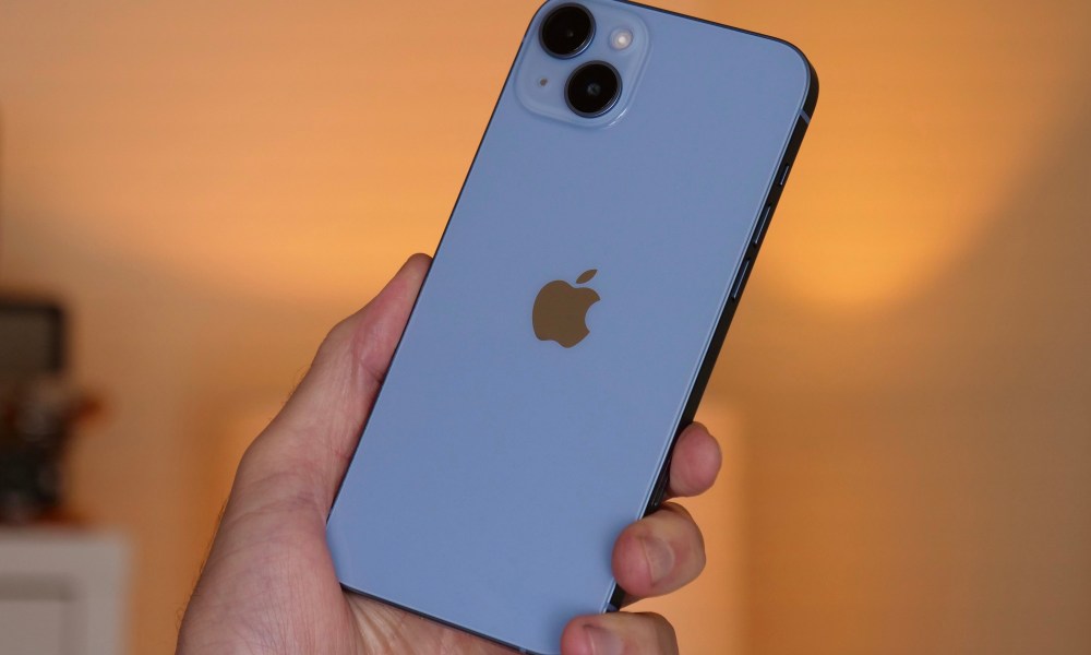 The iPhone 14 Plus held in a man's hand.