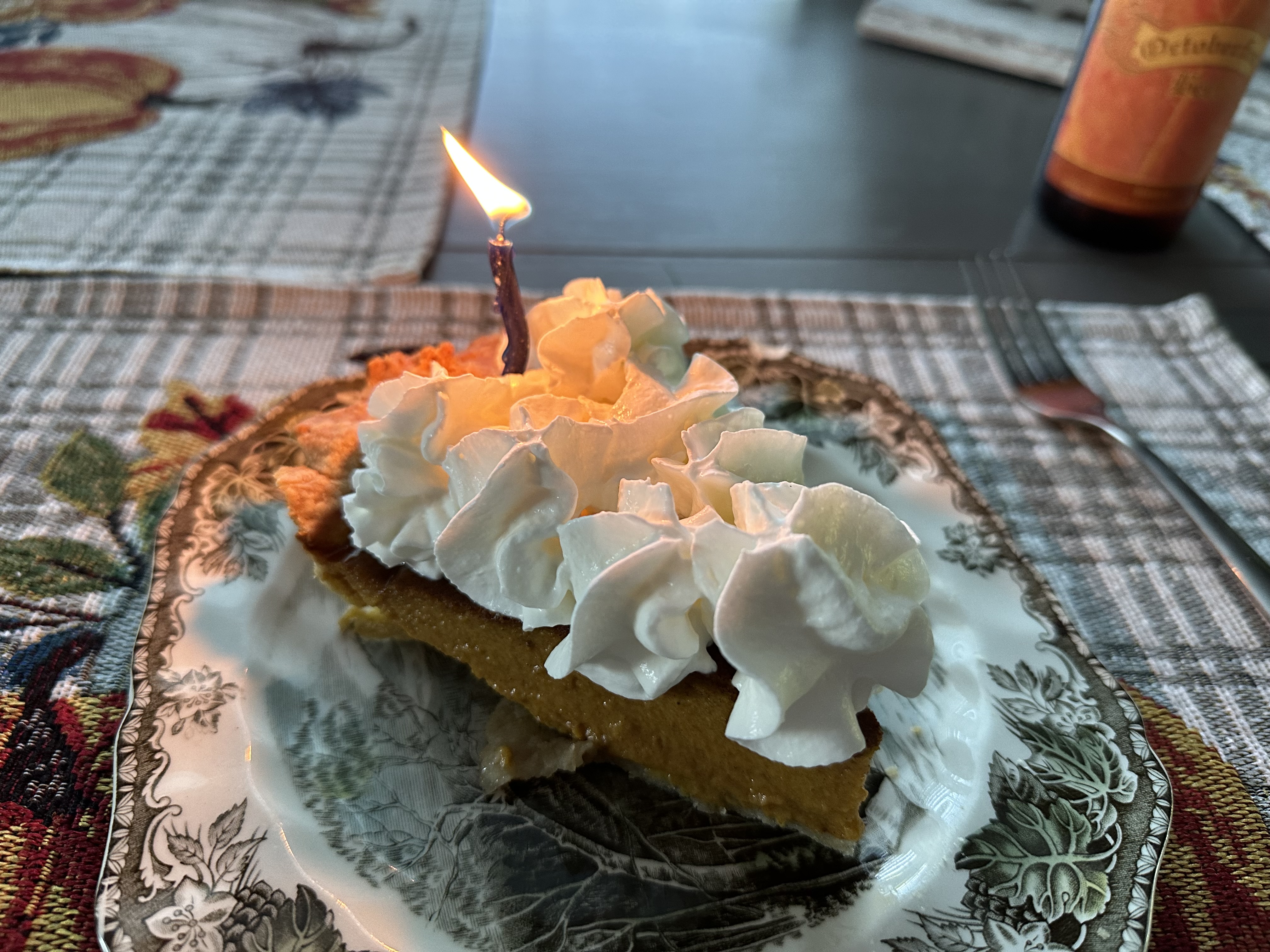 Photo of a pumpkin pie with a candle in it, taken with the iPhone 14 Pro Max.