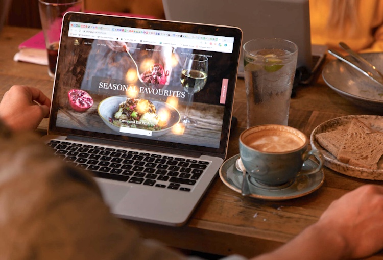 A laptop and a cup of coffee on a pub table.