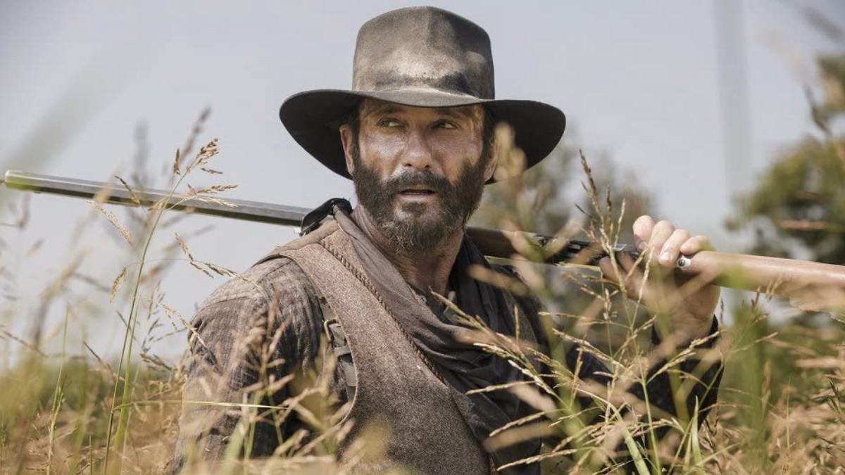 Tim McGraw holds a gun over his shoulder in a scene from 1883.