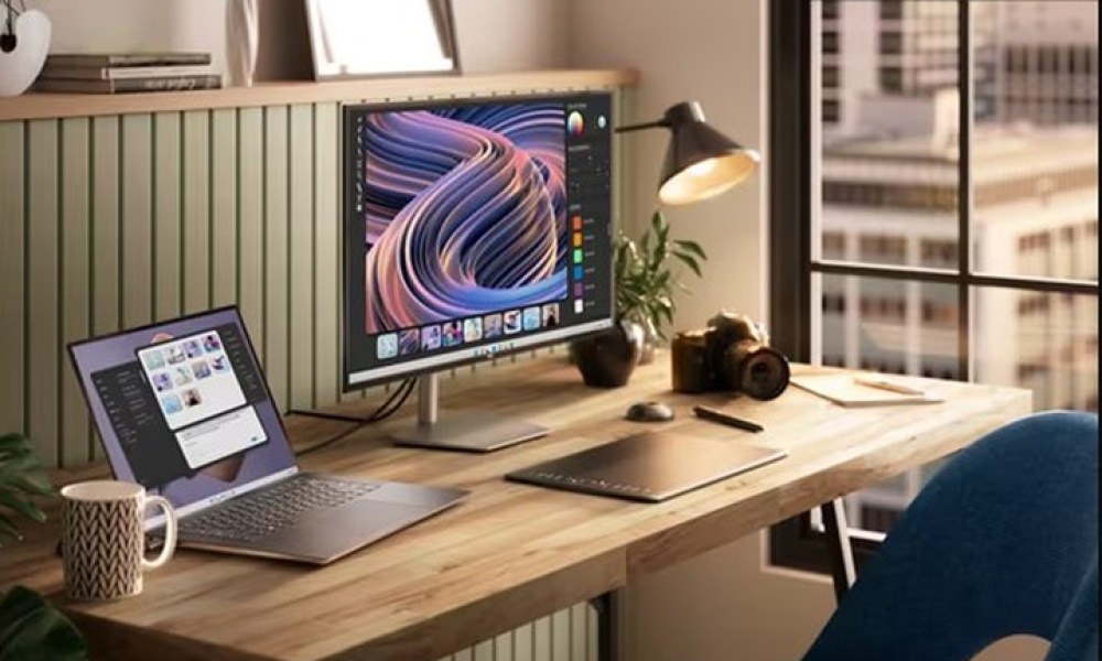 A Dell XPS 15 laptop on an office desk next to a monitor.