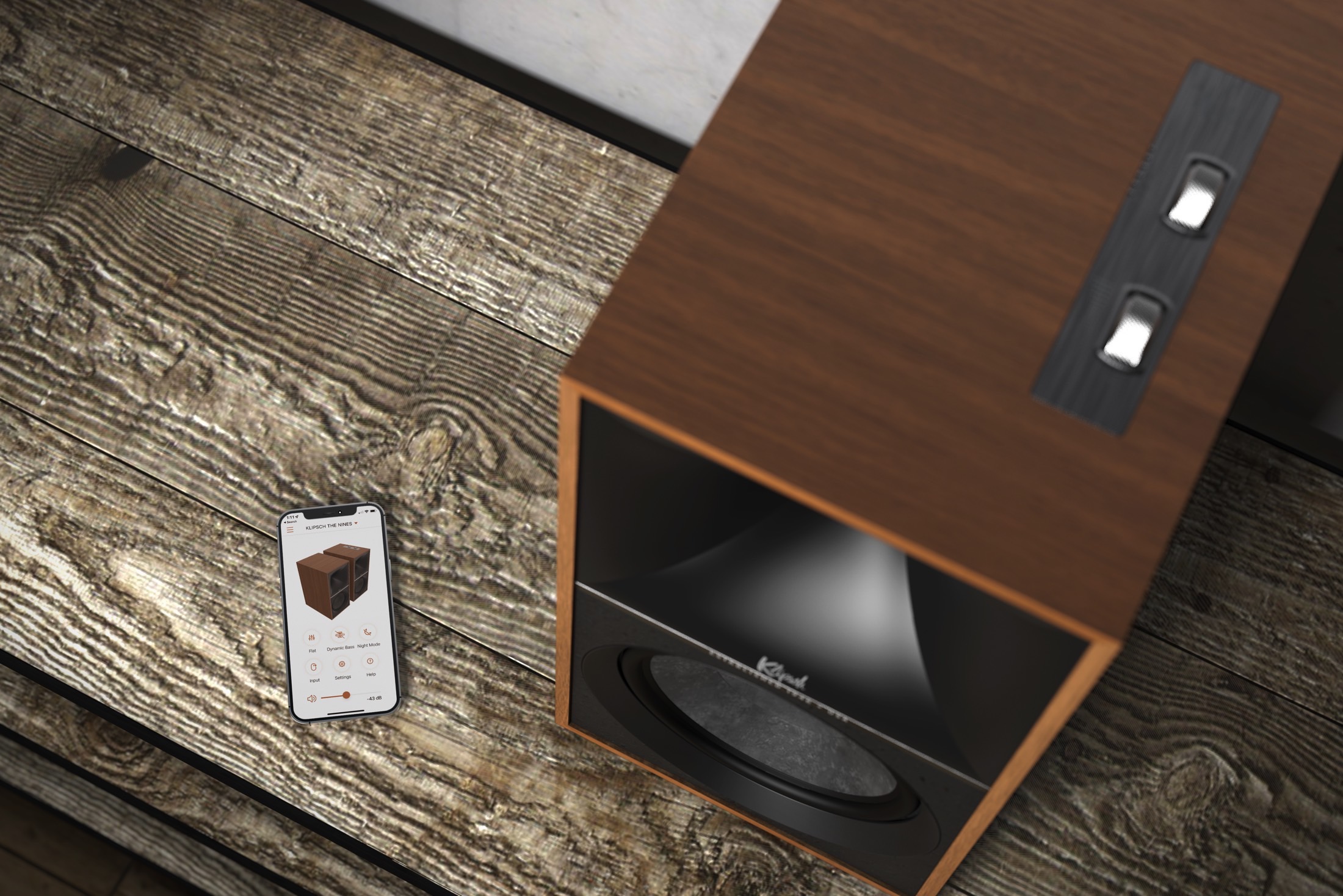 Klipsch The Nines in walnut finish seen next to a smartphone.