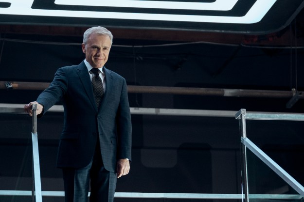 Christoph Waltz stands at the top of a staircase in The Consultant.