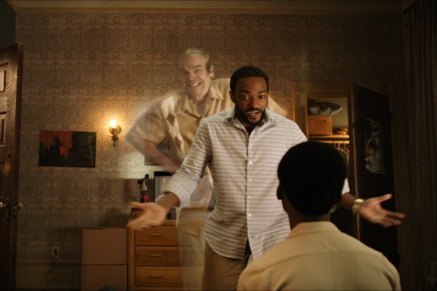 David Harbour, as a ghost, peeks out from behind Anthony Mackie in a scene from We Have A Ghost.