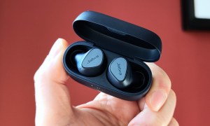 Jabra Elite 4 in an open charging case held by a hand.