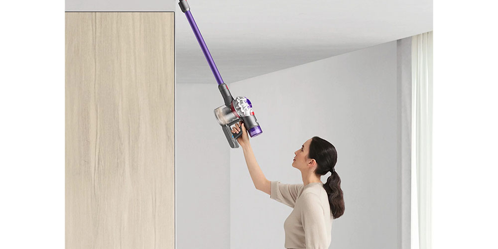 A woman lifting the Dyson V8 Origin+ above her head.