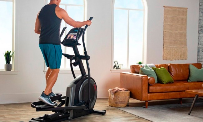 A man working out with the ProForm Carbon EL elliptical machine in a nice apartment.