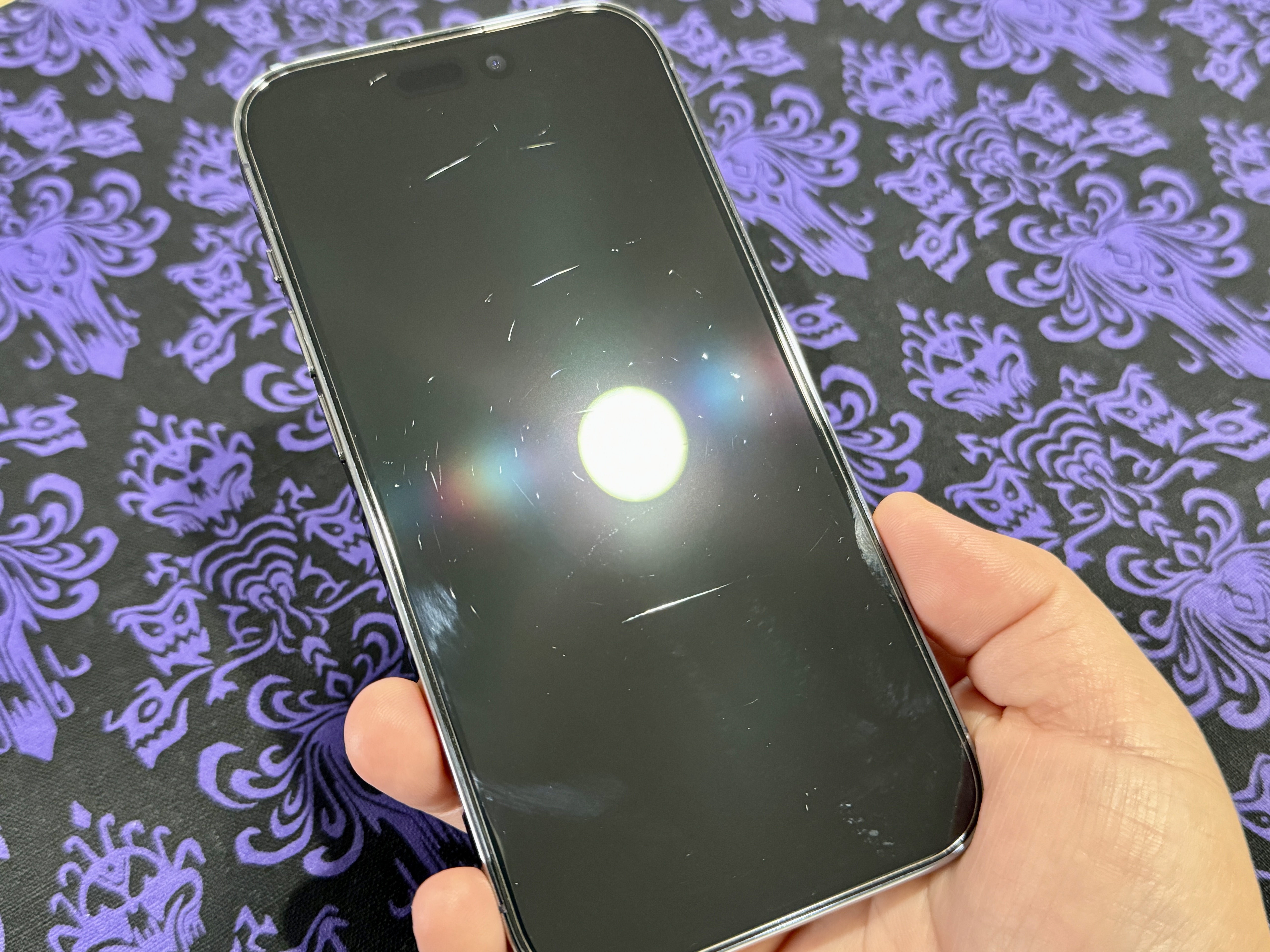 Light exposing more scratches on a screen protector on Christine's iPhone 14 Pro.