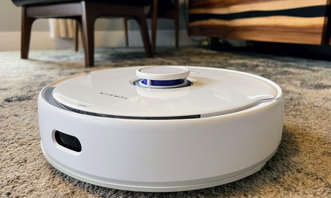 A Narwal robot vacuum sits on a living room carpet.