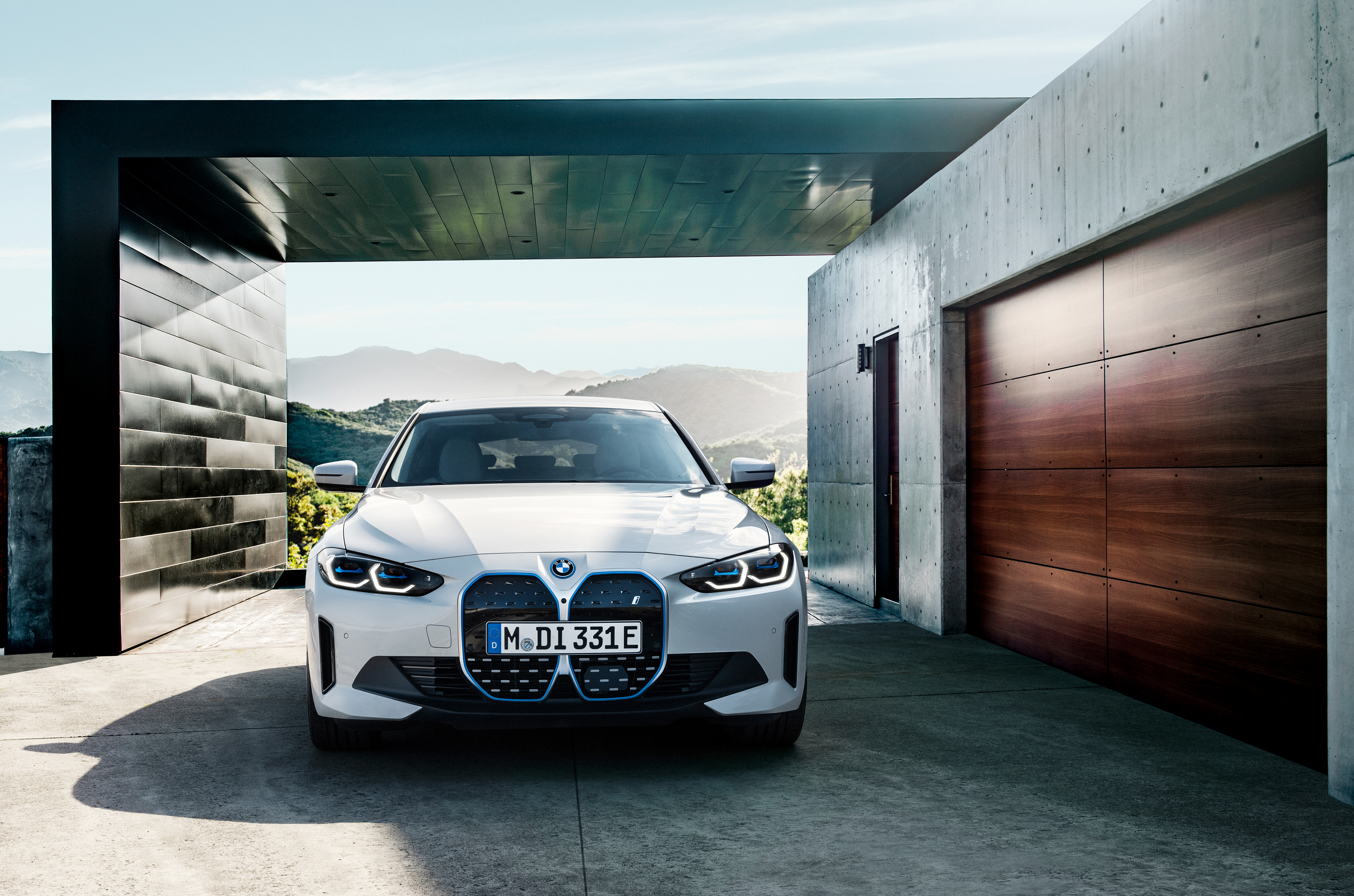 A BMW i4 parks in front of a modern building.