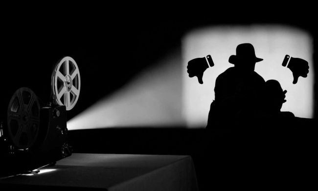 A film projector showing a fedora-wearing silhouette with two thumbs down icons.